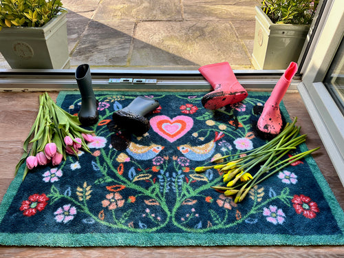 A floral front door mat with flowers and muddy wellies on top