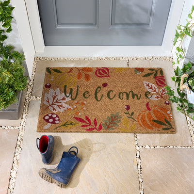 Discover the Autumnal Welcome Coir Doormat- a coir doormat featuring leaves, berries, pumpkins and mushrooms with a graphic font.