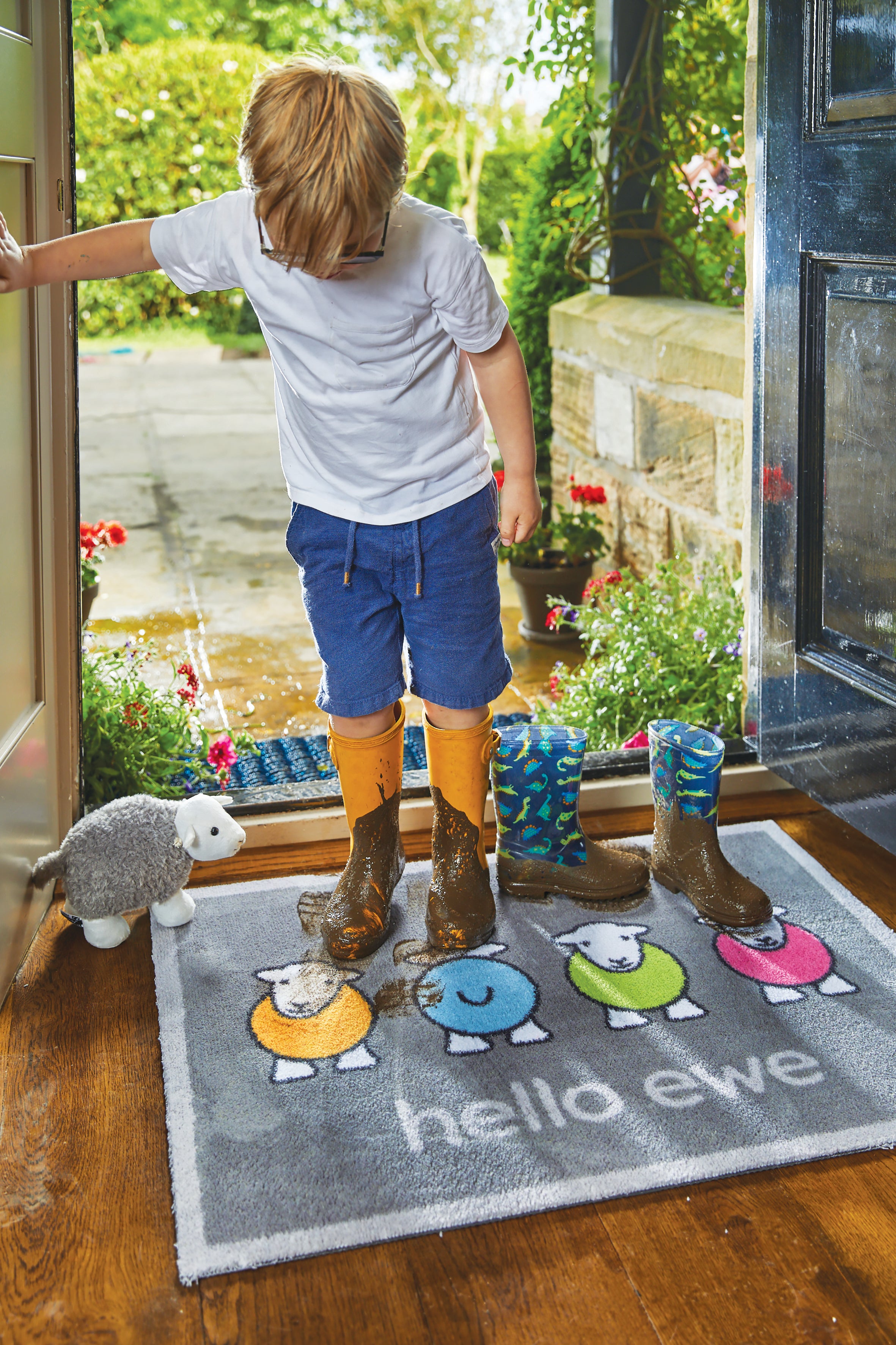 Young boy with muddy boots walking onto a Hello Ewe mat