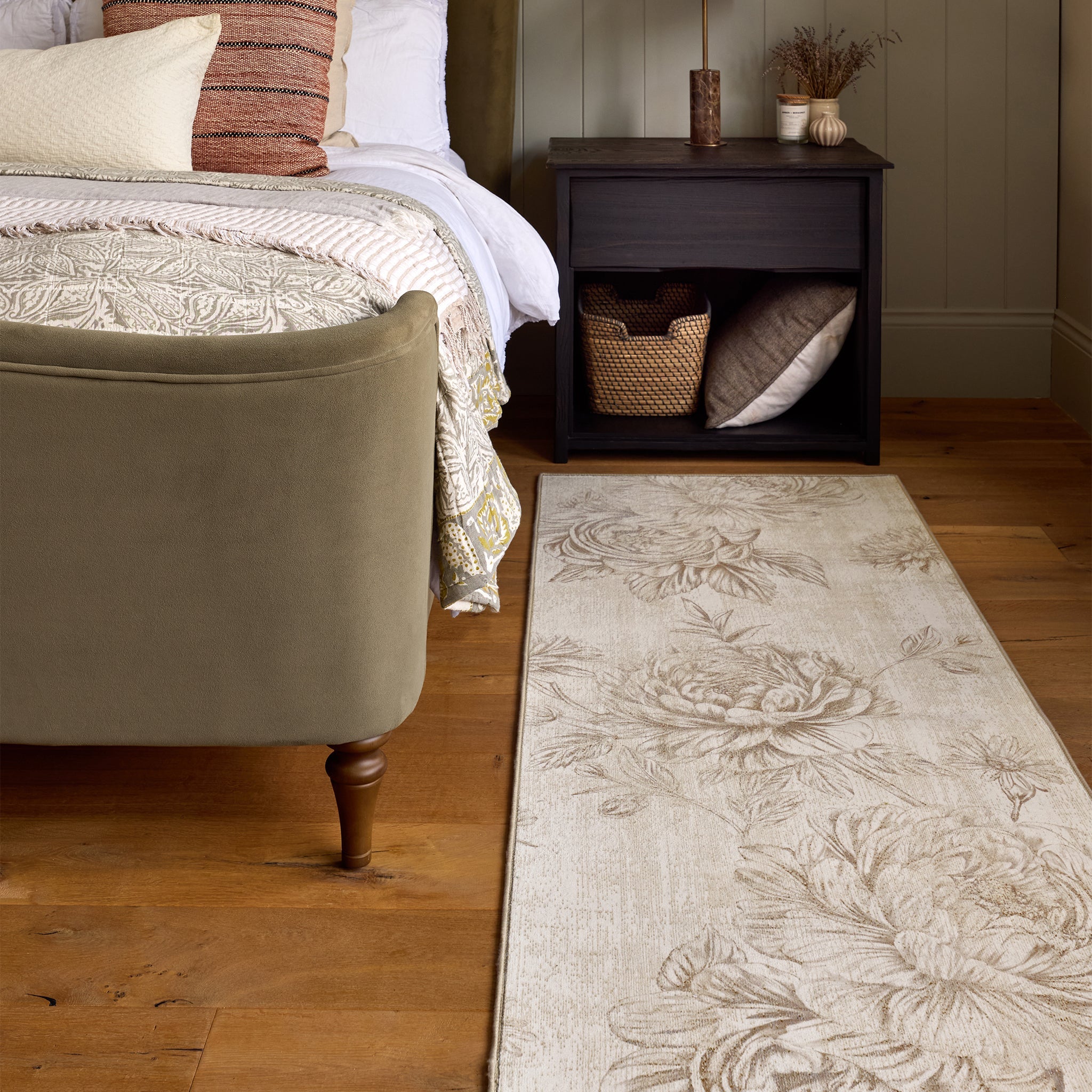 Bedroom with floral-patterned rug in muted beige tones, bed, and nightstand.