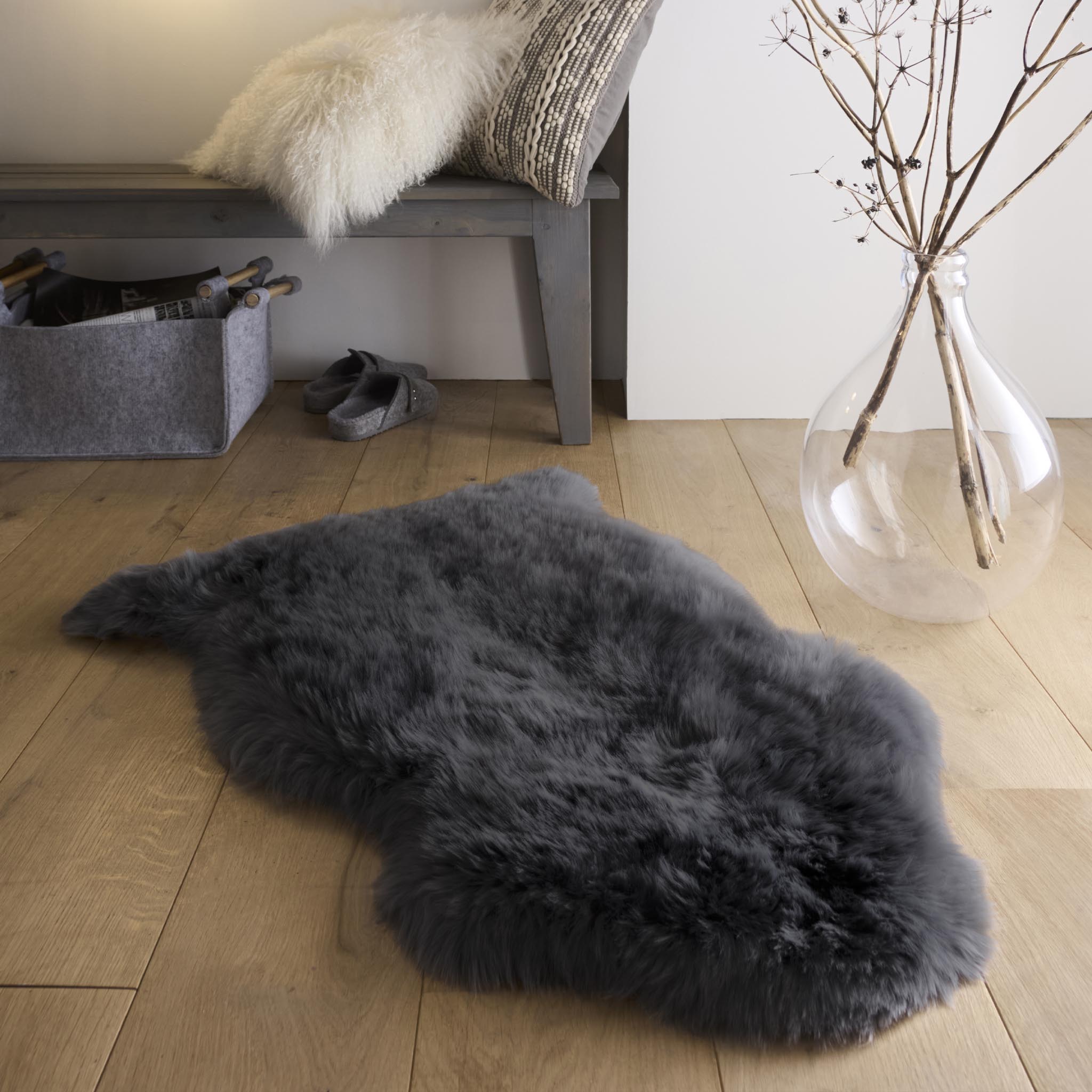 Plush black single sheepskin rug on a wooden floor.