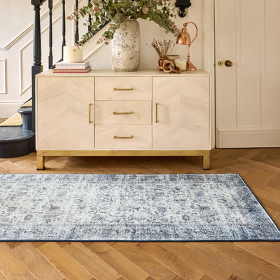 Hallway showing a runner in a vintage blue and grey pattern on wooden floor with a cabinet in the background