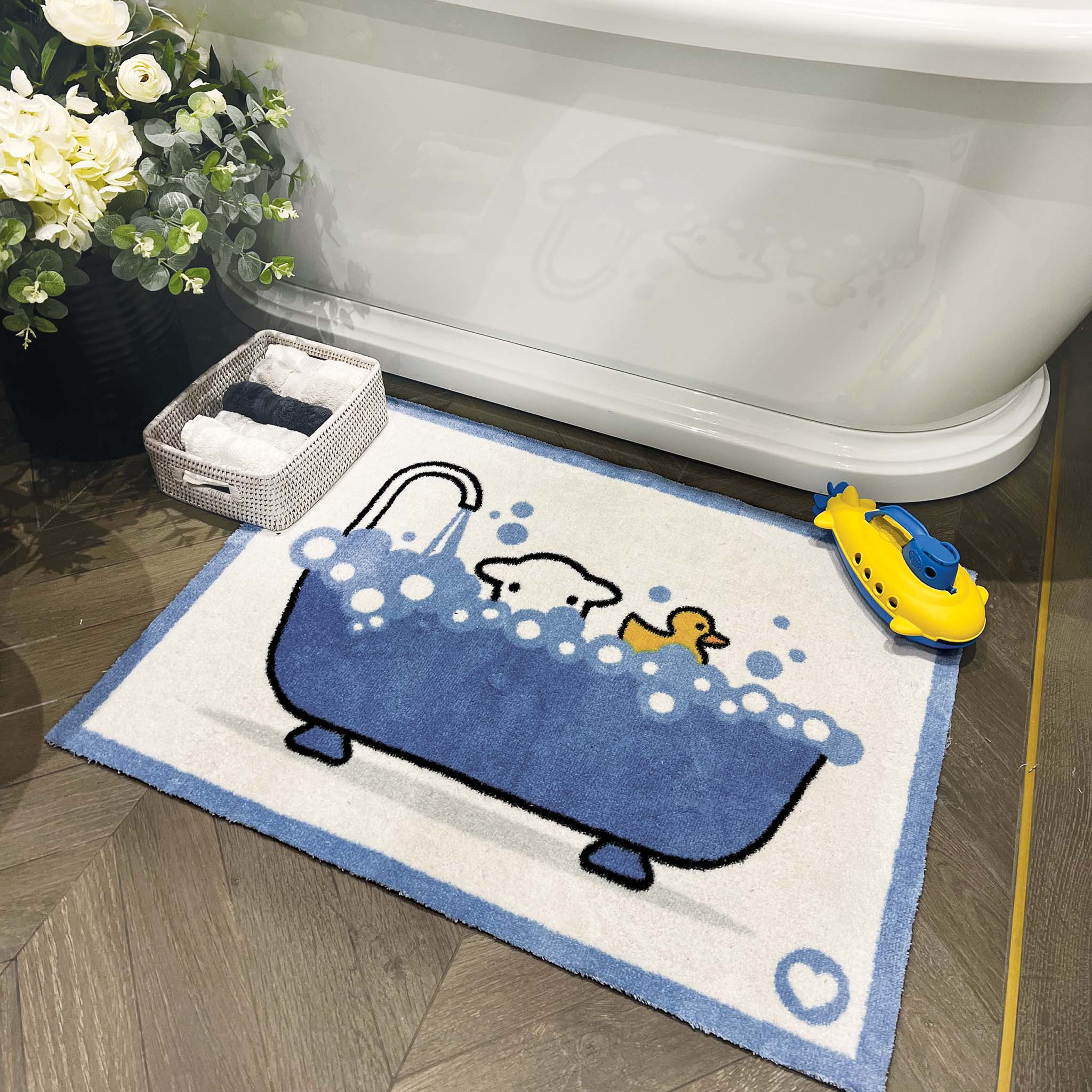 Lifestyle image of a Bathtime Herdy washable bath mat from Hug Rug next to a bath tub