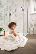 Boy sat on bathroom floor wrapped in a towel