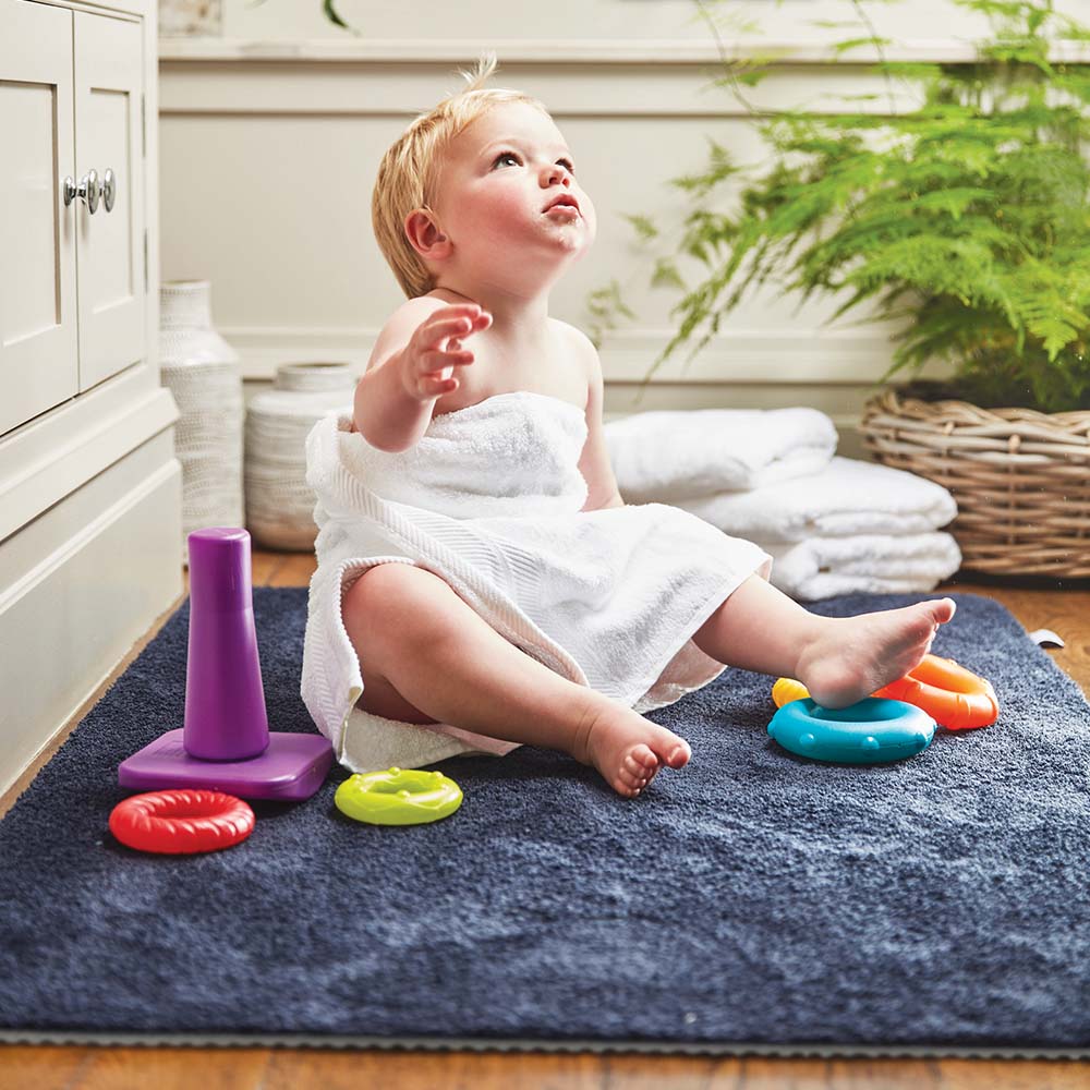 toddler wrapped in towel sat on a blue mat