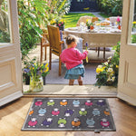Lifestyle image of a young girl stood in front of a grey marra Herdy washable doormat from Hug Rug