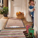 Lifestyle image of a young child stood next to a Peep Stripe Herdy washable doormat and washable hallway runner from Hug Rug