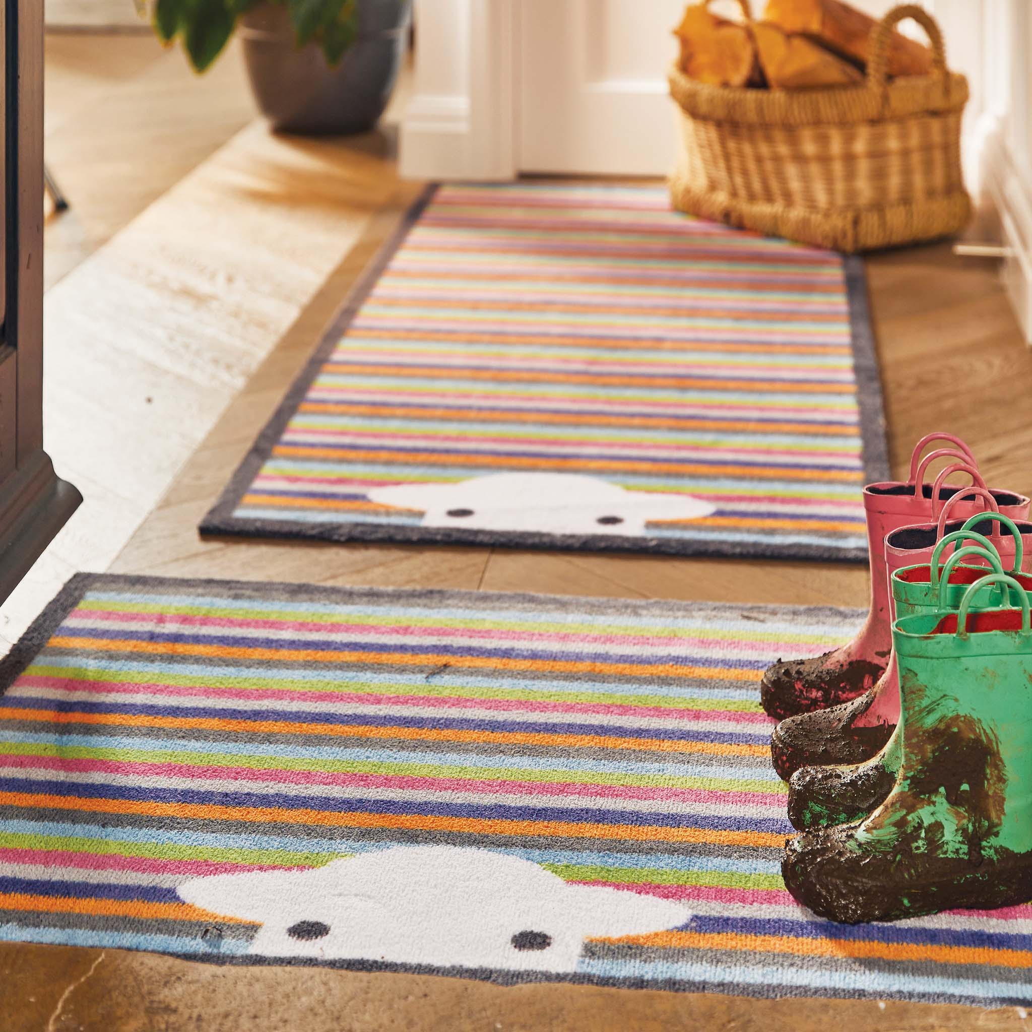Lifestyle image of muddy wellies on a Peep Stripe Herdy washable doormat and washable hallway runner from Hug Rug