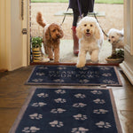 Lifestyle image of three dogs walking across a navy Pet 10 washable doormat and washable runner from Hug Rug