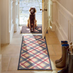 Lifestyle image of dog sat on Hug Rug black tartan paw washable  doormat and matching runner