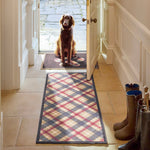 Lifestyle image of dog sat on Hug Rug black tartan paw washable  doormat and matching runner