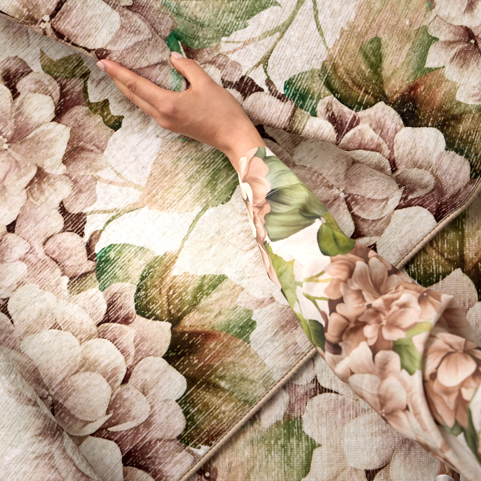 Hand holding a floral-patterned rug with a close-up of the pattern
