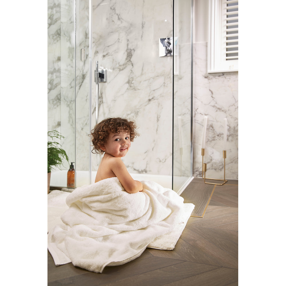 Boy sat on bathroom floor wrapped in a towel