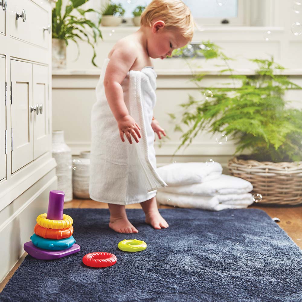 toddler wrapped in towel stood on a blue mat