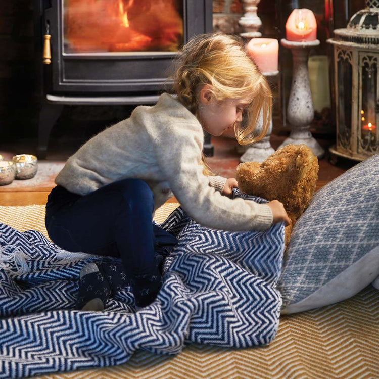 Little girl wrapping her teddy bear in a blue throw